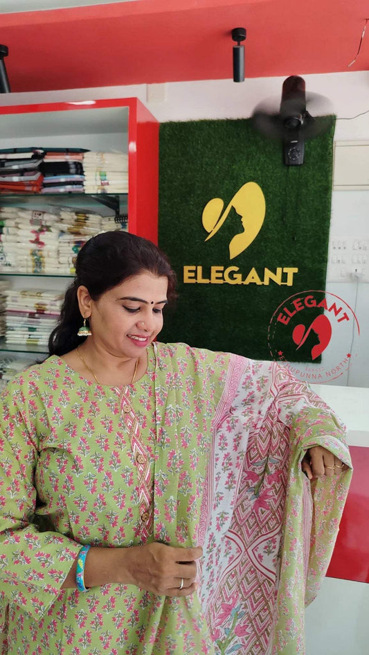 Woman showcasing a pink and green cotton churidar set in a boutique with Elegant brand logo in the background.