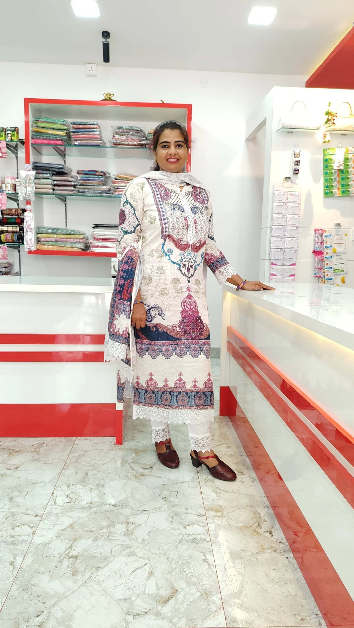 Woman wearing white and purple printed Kora Maslin fabric churidar set in a clothing store interior