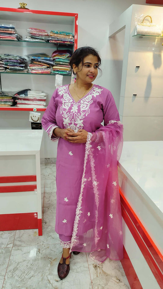 Pink silk churidar set with white embroidery and matching net dupatta worn by woman in boutique