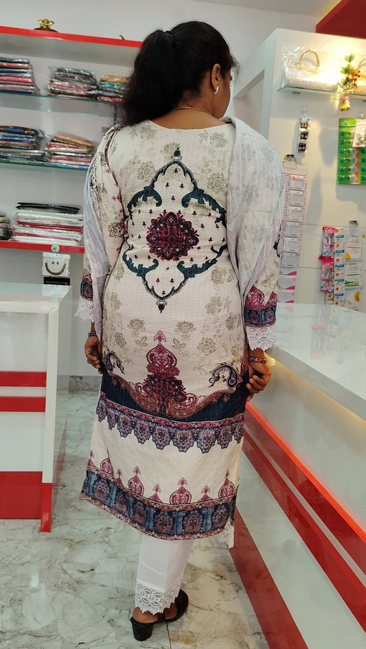 Woman wearing white and patterned churidar set with intricate back design in a clothing store interior