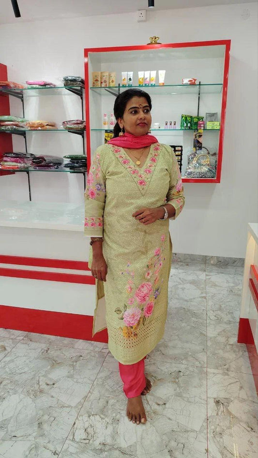 Woman wearing beige cotton churidar set with pink floral embroidery and matching pink dupatta in a modern store setting