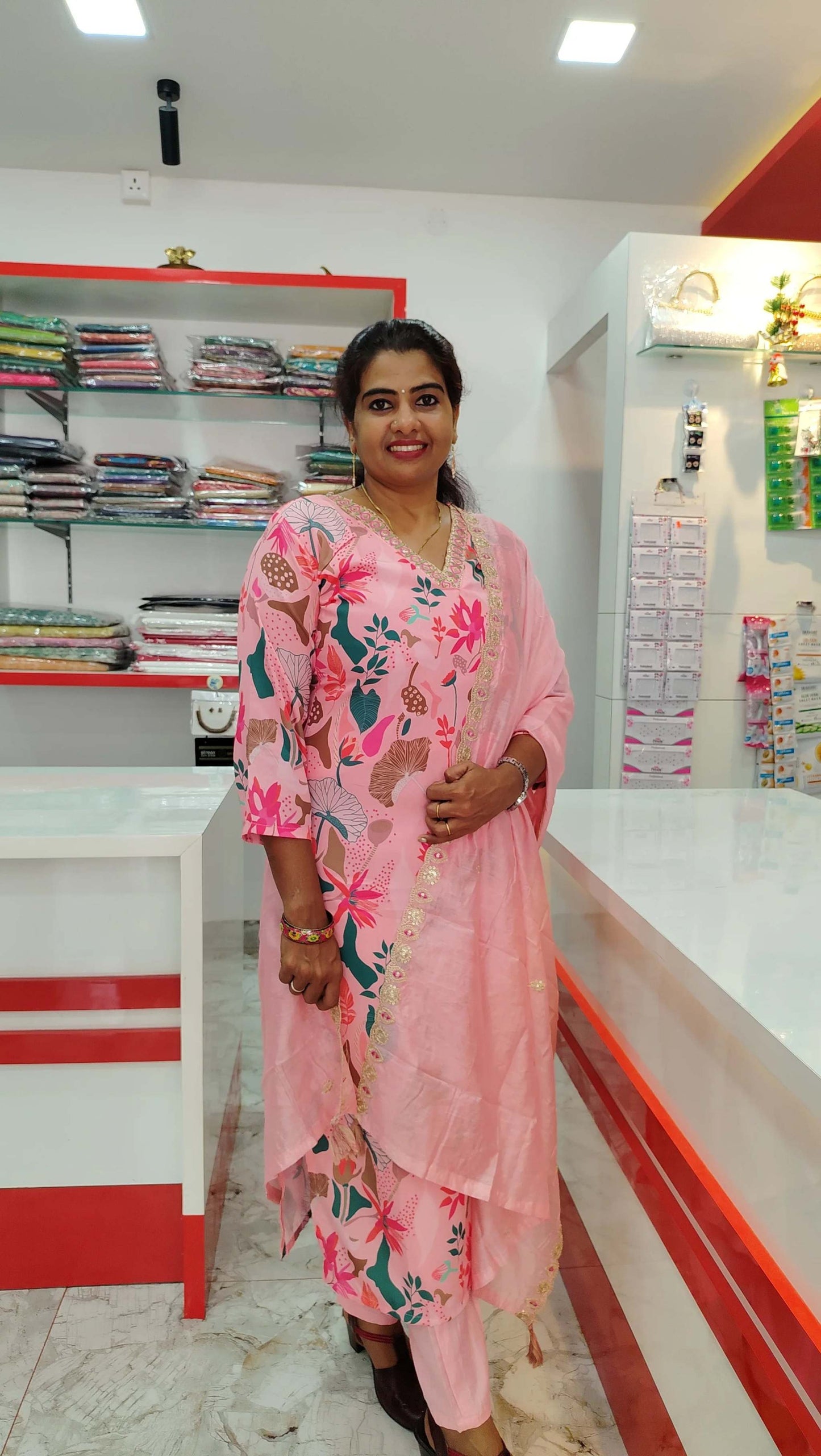 Woman wearing a pink floral viscose maslin churidar set standing in a fabric store.