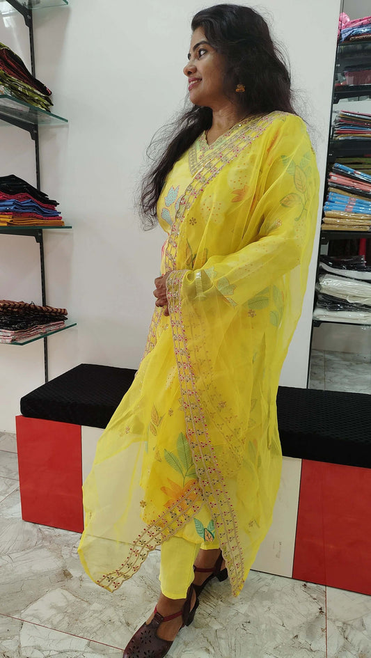 Woman wearing yellow silk churidar set with floral embroidery in a boutique setting
