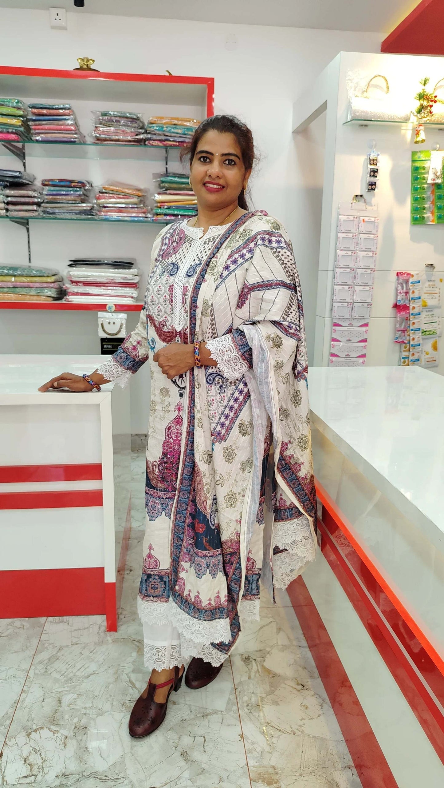 Woman wearing white and printed churidar set standing inside a fabric store