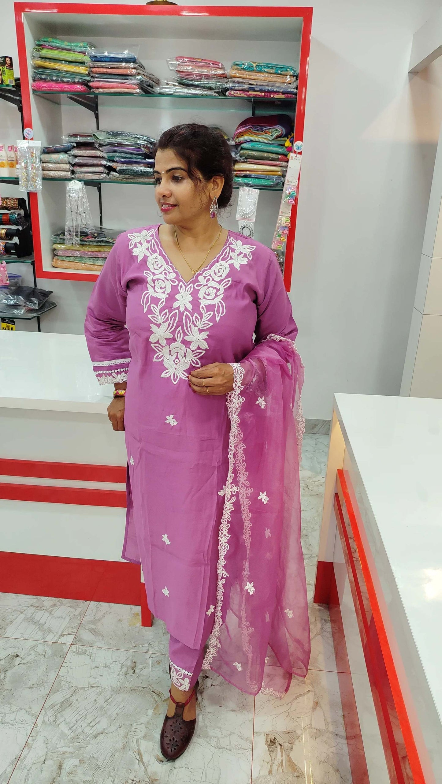 Woman wearing pink silk churidar set with white embroidery and matching dupatta in a clothing store