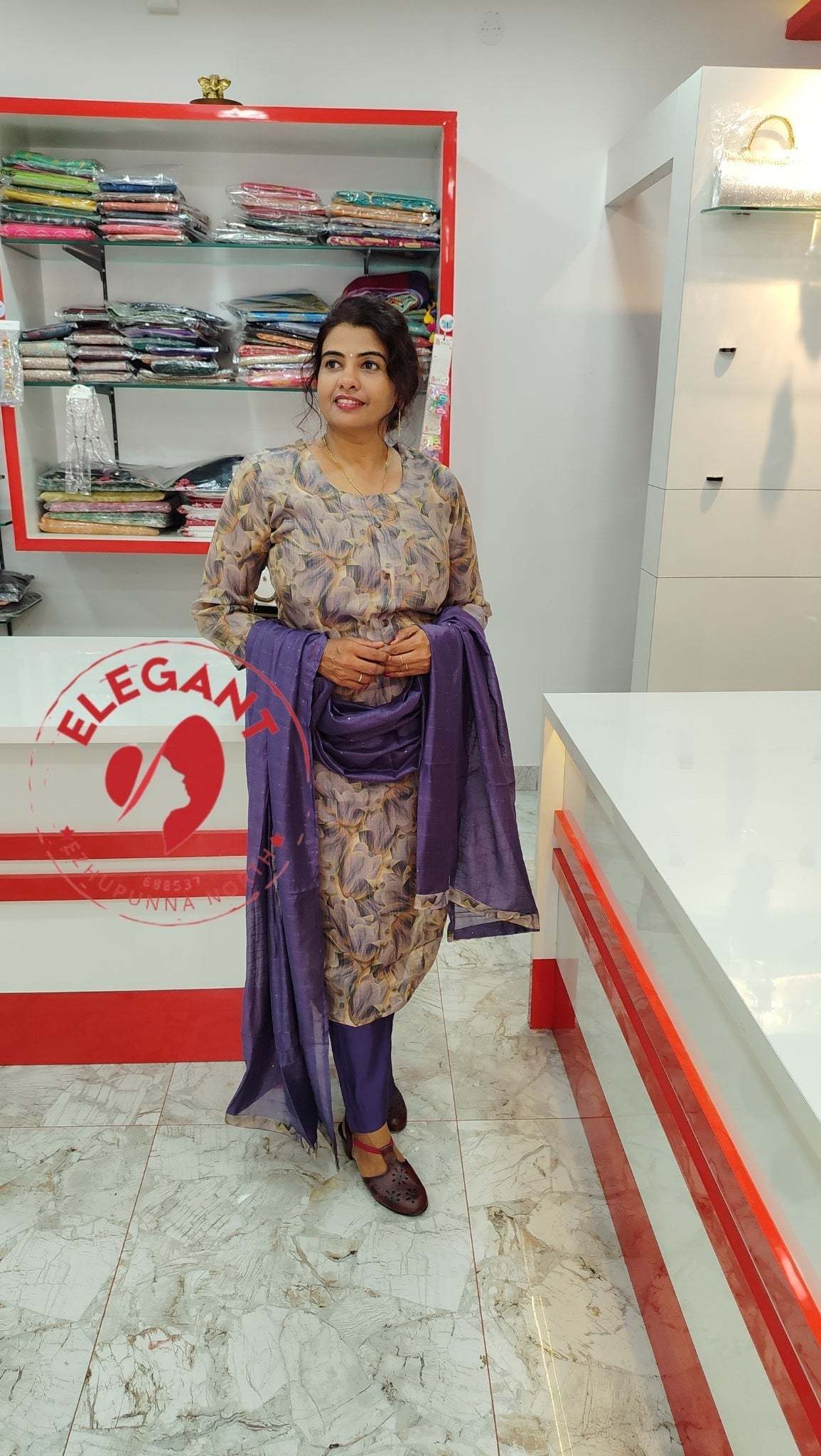 Woman wearing a shimmer fabric Churidar set in purple tones, standing inside a clothing store.