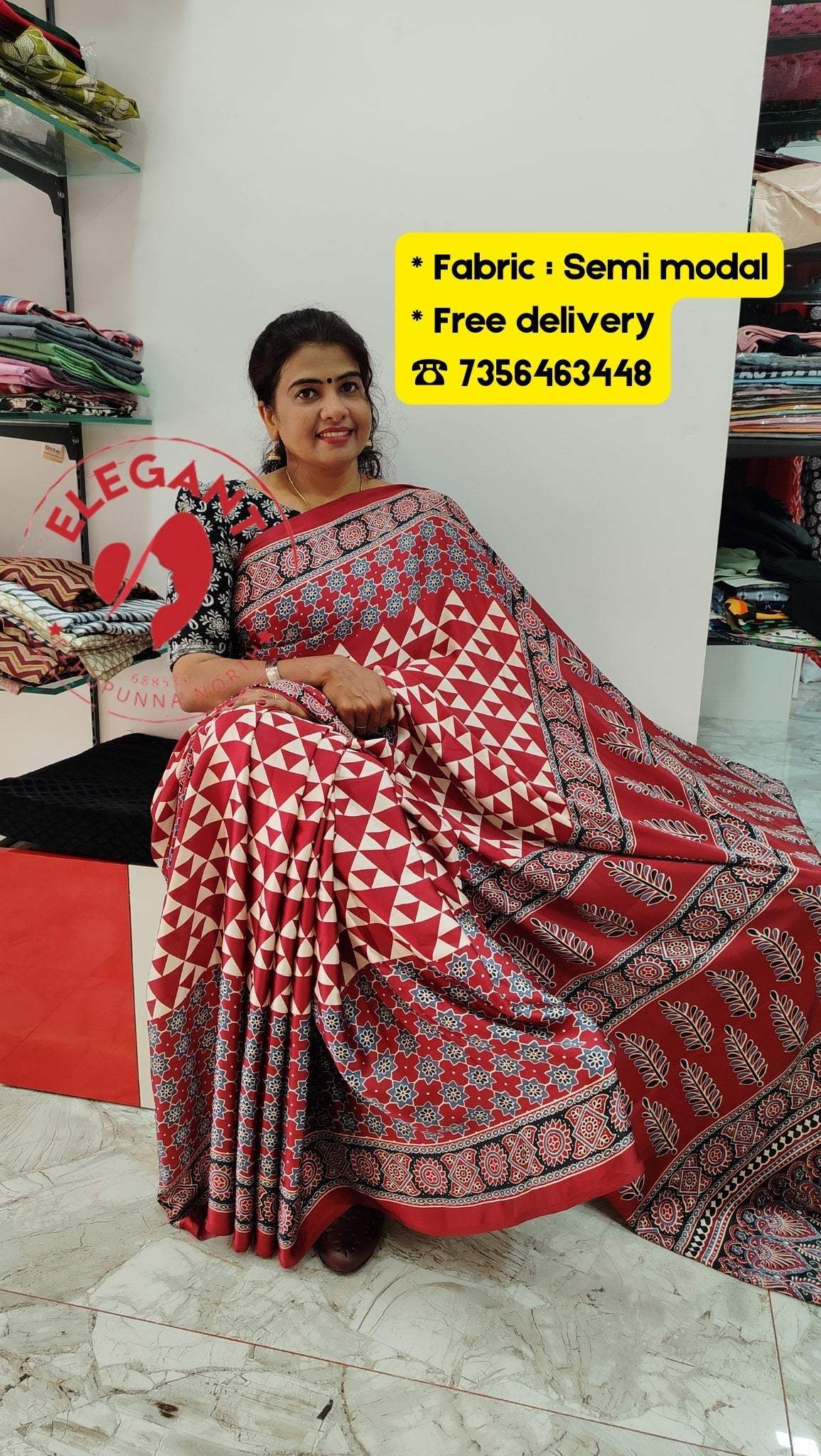 Woman wearing a red and white geometric patterned semi modal silk saree sitting indoors with fabric and free delivery information displayed.