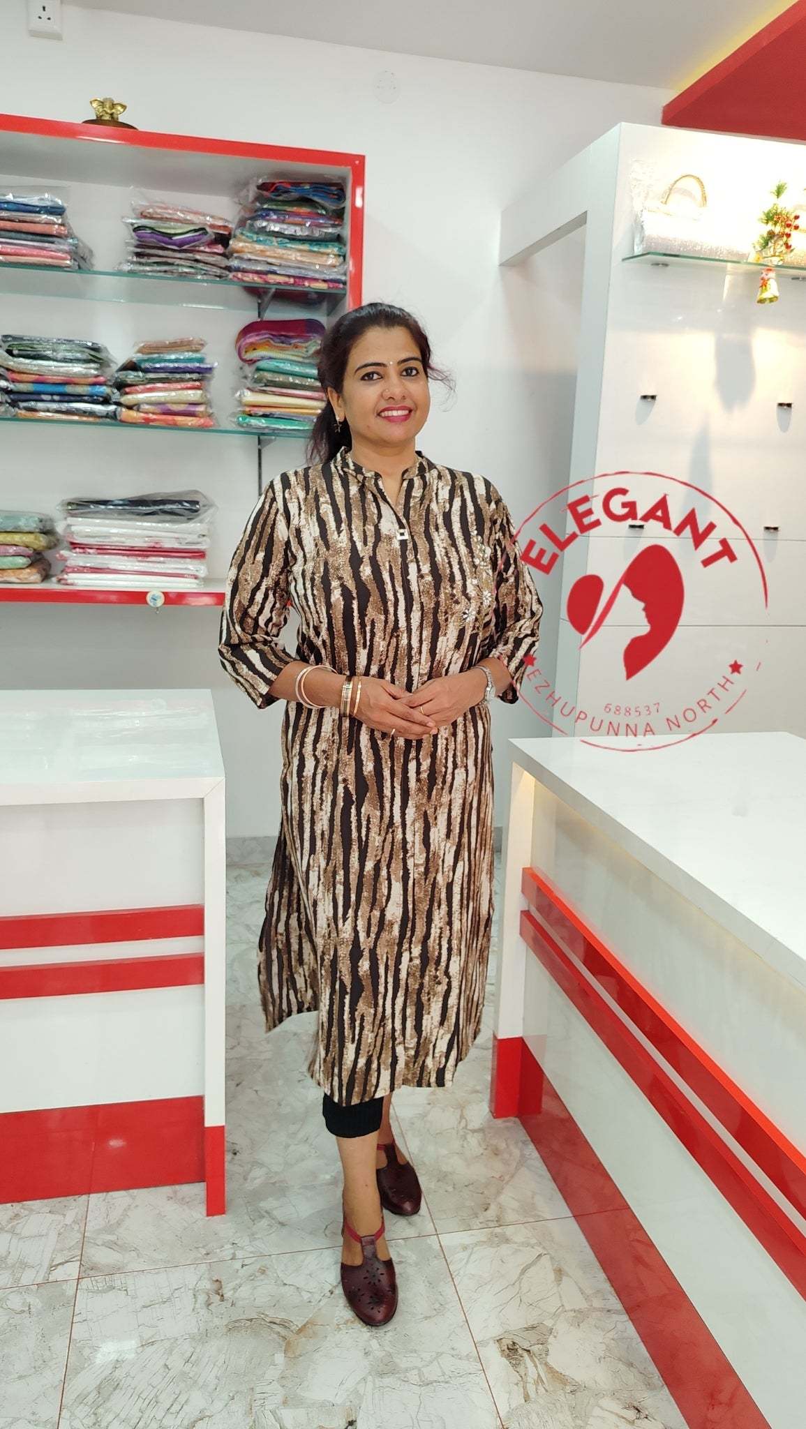 Woman wearing an elegant imported crepe top with a black and beige pattern, standing in a modern store setting.