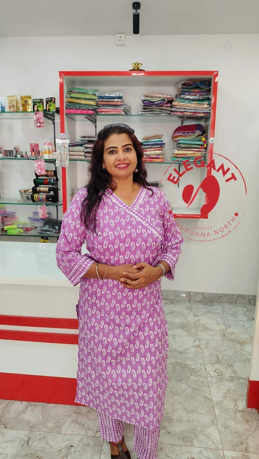 Woman wearing a pink and white cotton Kurthi Set standing in a clothing store.