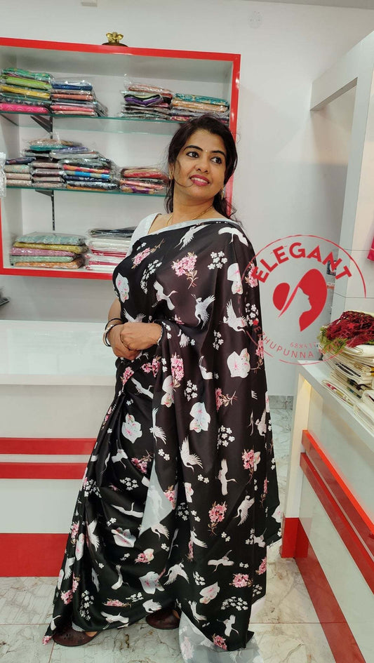 Woman wearing black floral satin silk saree in clothing store with fabric shelves in background