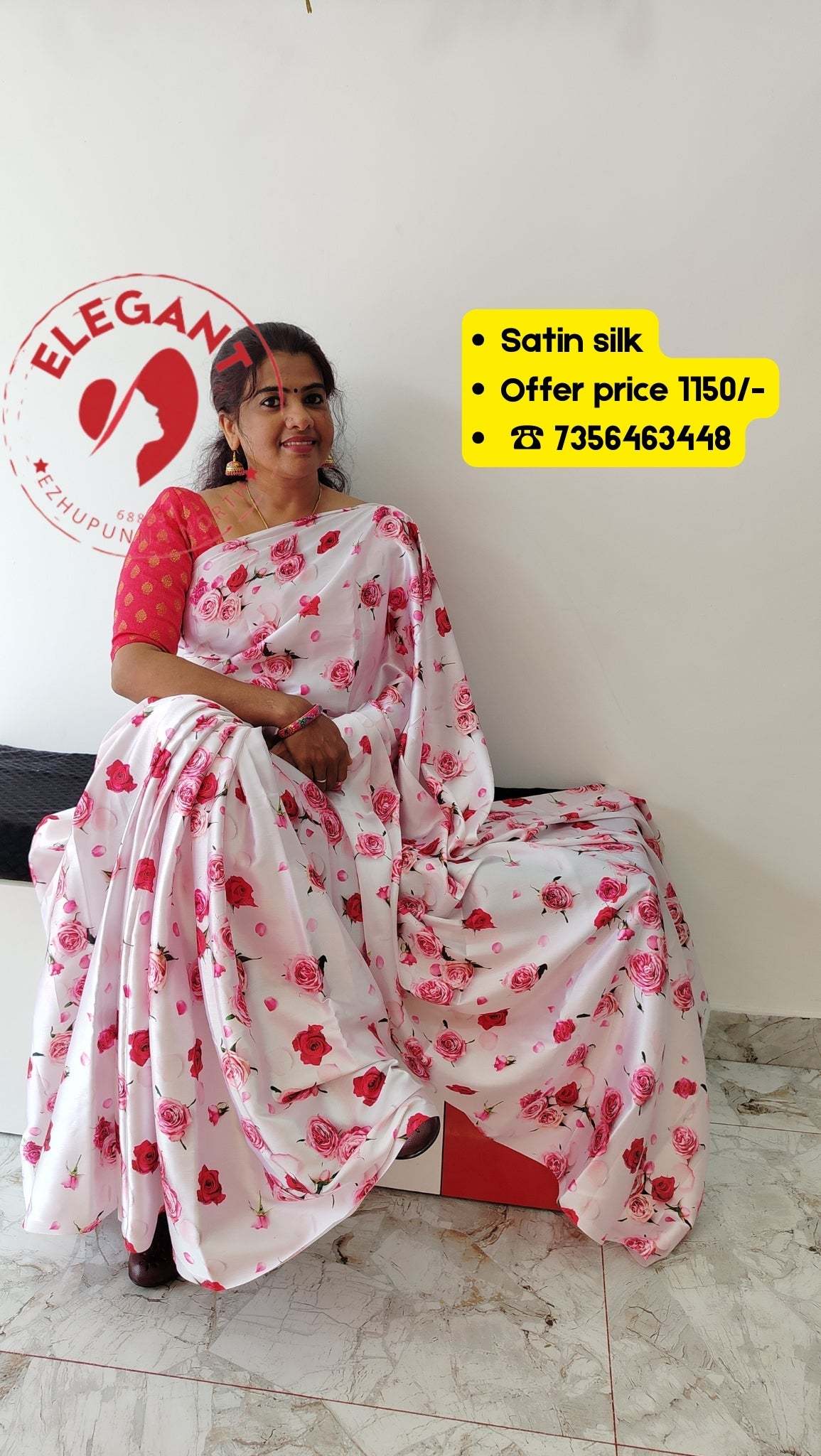 White satin silk saree with pink floral print and matching pink blouse worn by a woman sitting indoors