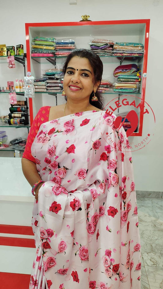 Woman wearing a pink floral satin silk saree in a fabric store showcasing satin silk sarees for occasion and party wear.