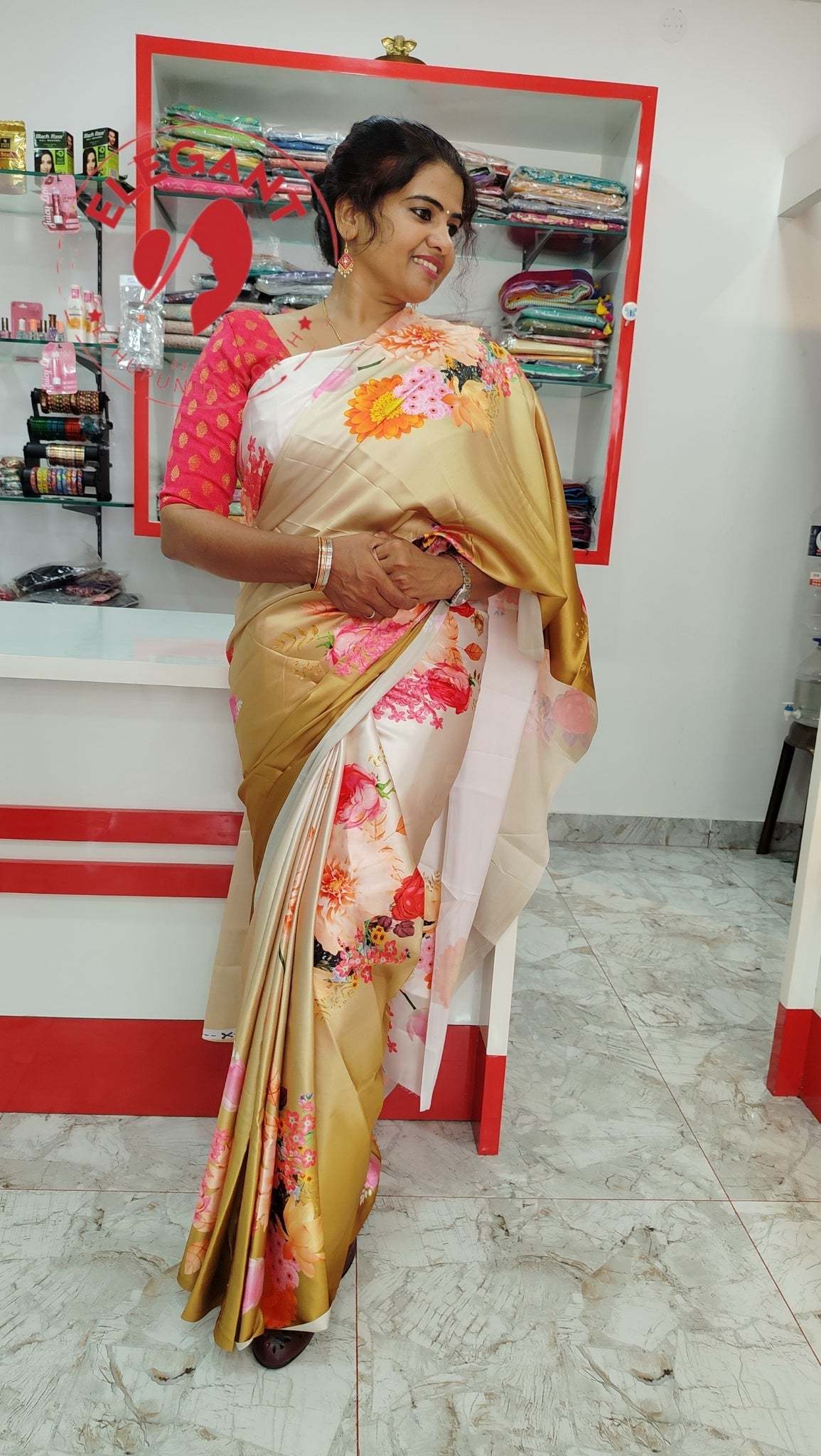 Woman wearing a golden floral satin silk saree with a pink blouse in a store setting