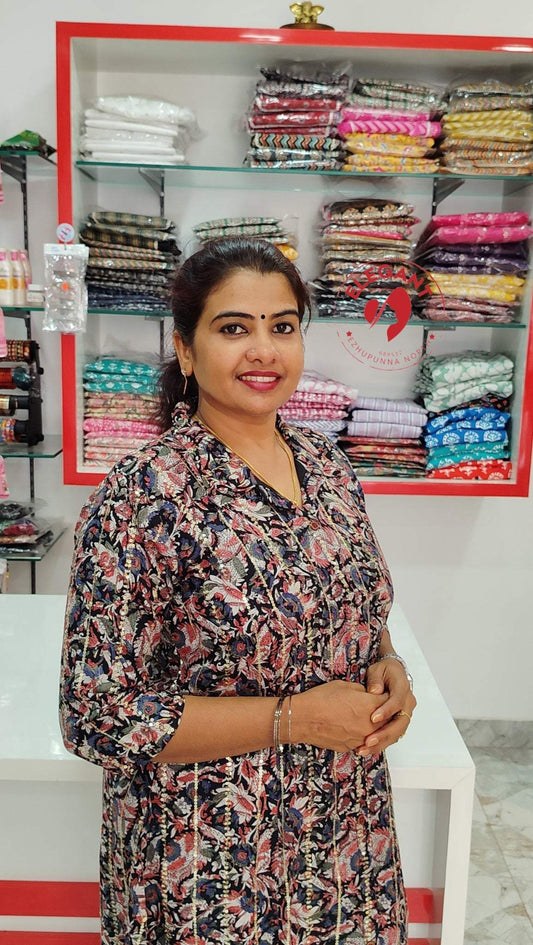 Woman wearing a stylish imported crepe top with intricate floral patterns in a fabric store with neatly stacked clothes on shelves behind her