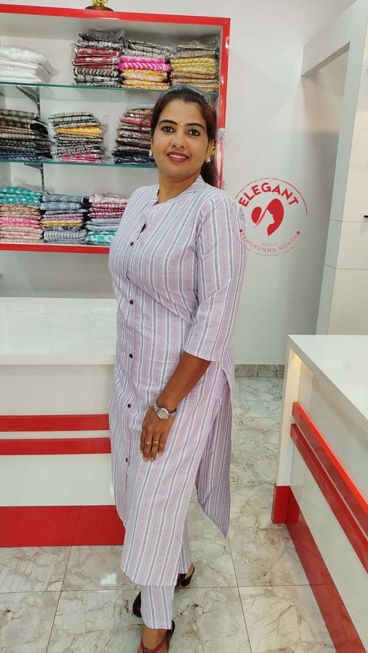 Woman wearing a striped Khadi kurthi set standing in a fabric store showcasing traditional and modern design.