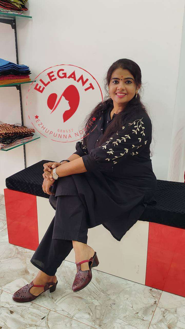 Woman wearing a black cotton Kurthi Set with floral embroidery, seated indoors in a stylish and comfortable look.