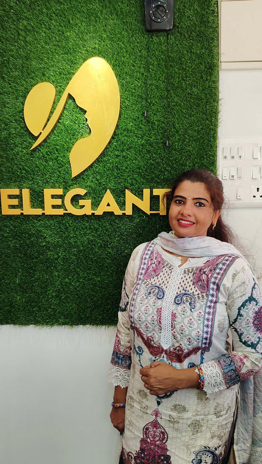 Woman wearing a printed Kora Maslin churidar set standing in front of an Elegant store sign.