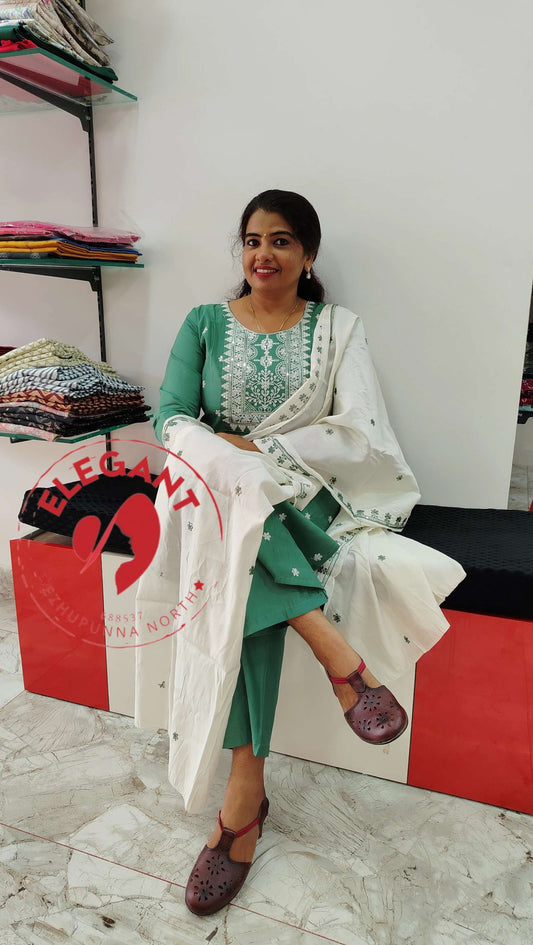 Green silk churidar set with white embroidered dupatta worn by woman sitting indoors