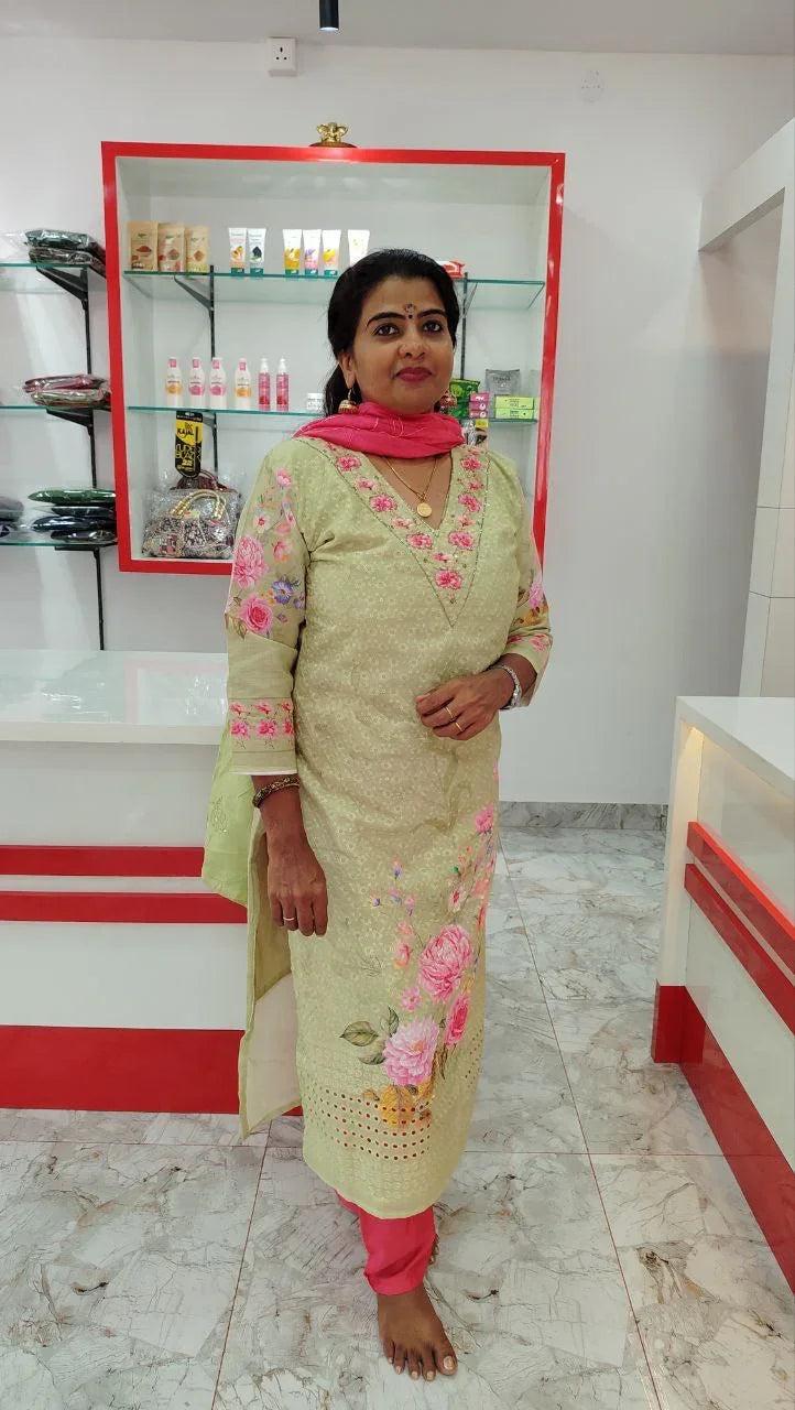 Woman wearing beige cotton churidar set with pink floral embroidery and pink churidar pants in a modern retail setting