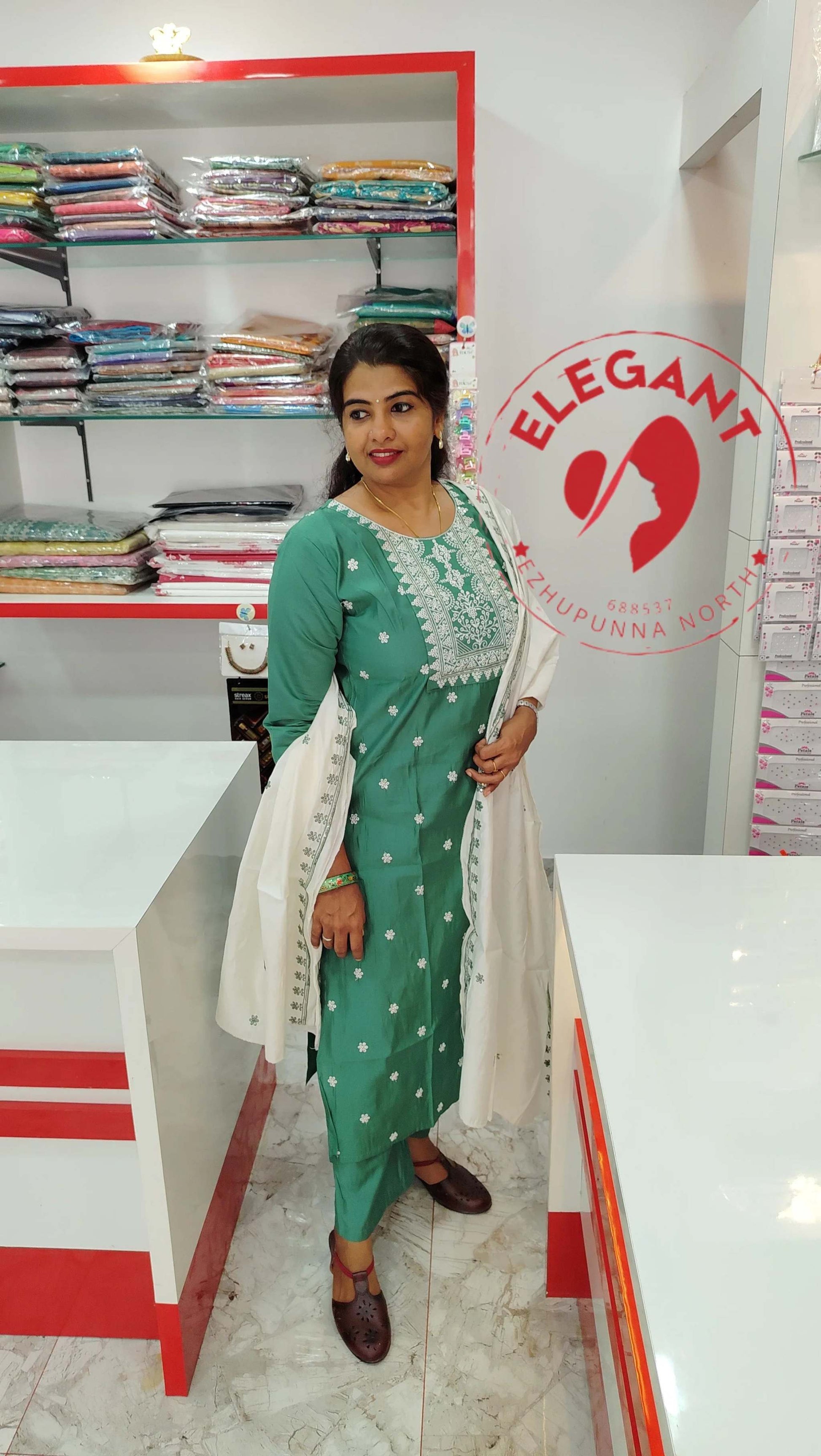Woman wearing green silk churidar set with white embroidery and matching dupatta in a fabric store interior