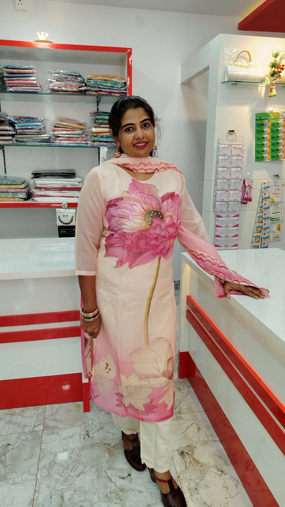 Woman wearing a cream and pink floral printed churidar set standing in a fabric store.