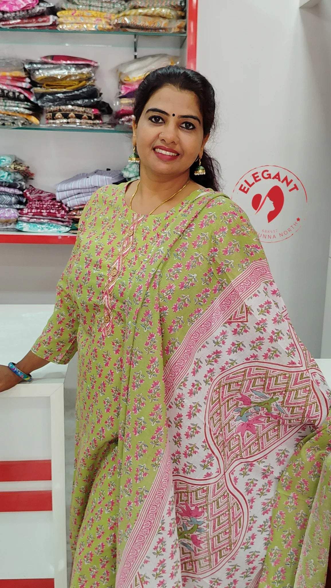 Woman wearing a green floral cotton churidar set with pink patterned dupatta in a clothing store