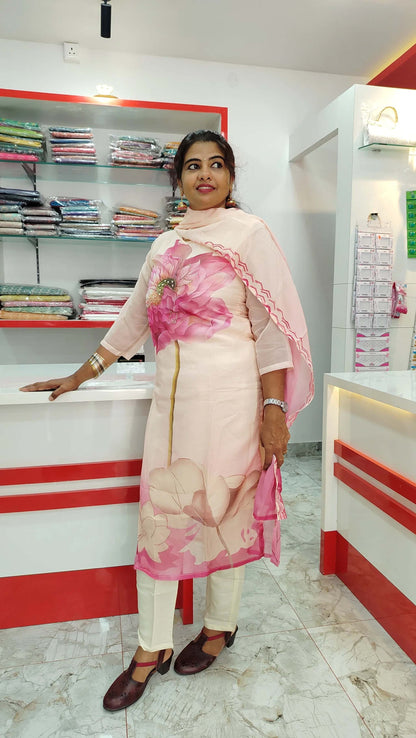Woman wearing light pink churidar set with floral print posing in a fabric store interior