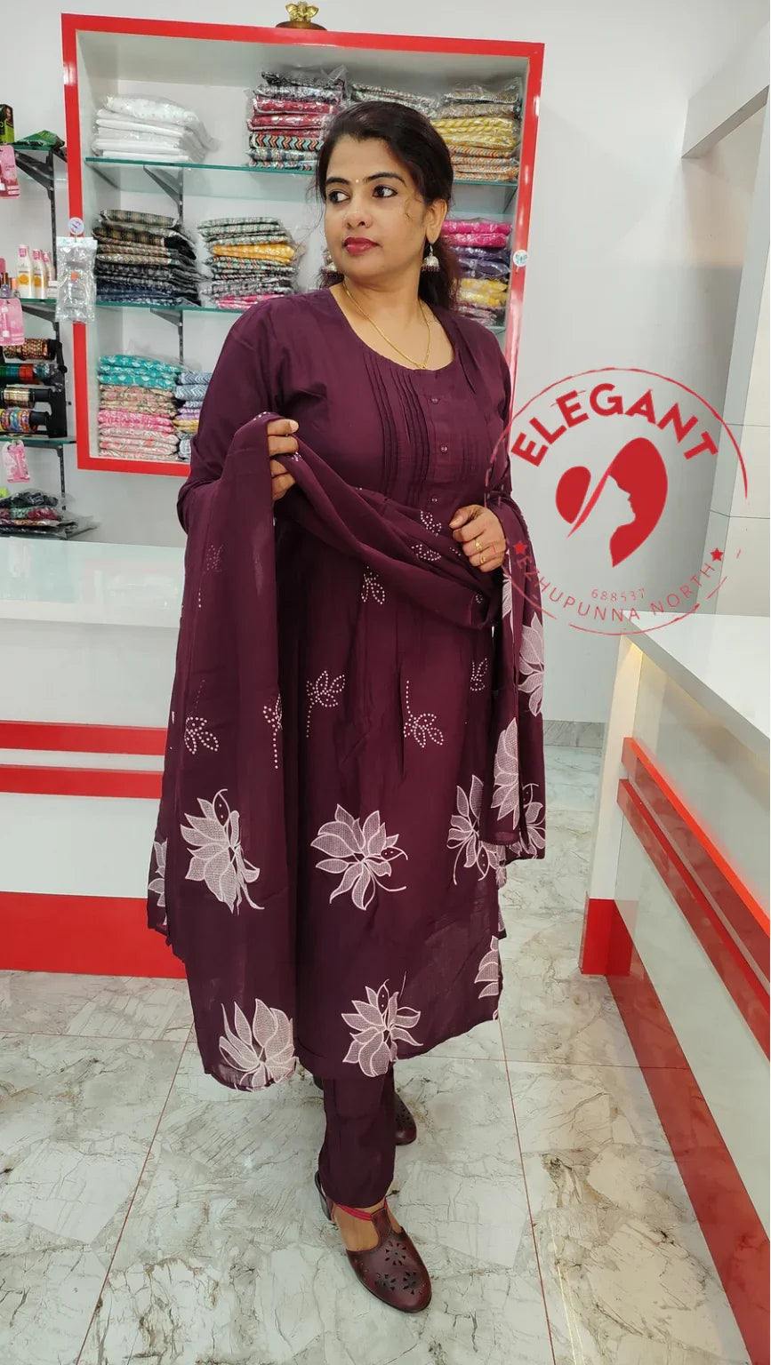 Woman wearing maroon mul mul cotton churidar set with white floral prints in a clothing store