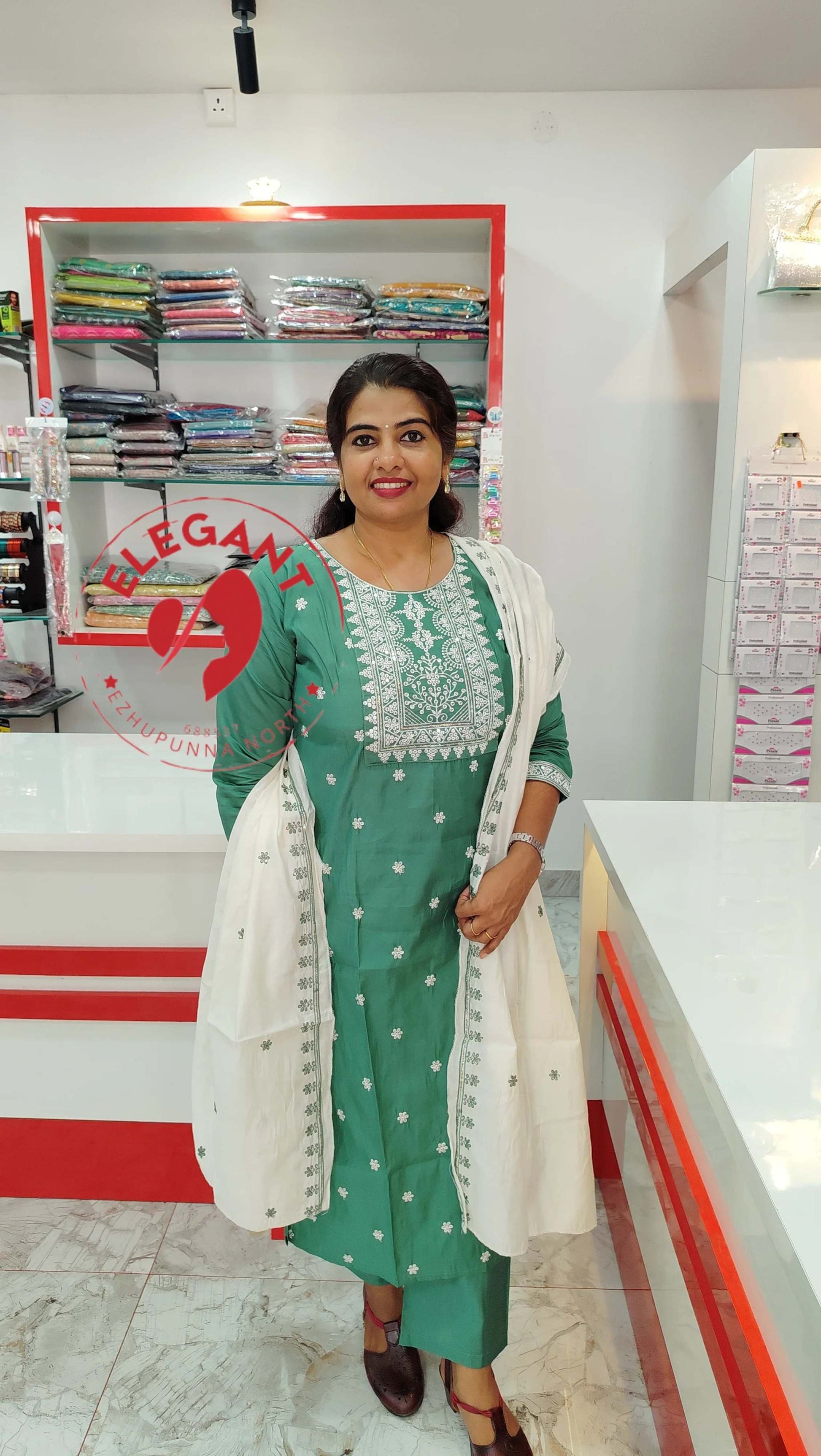 Woman wearing green silk churidar set with white embroidered dupatta in a clothing store