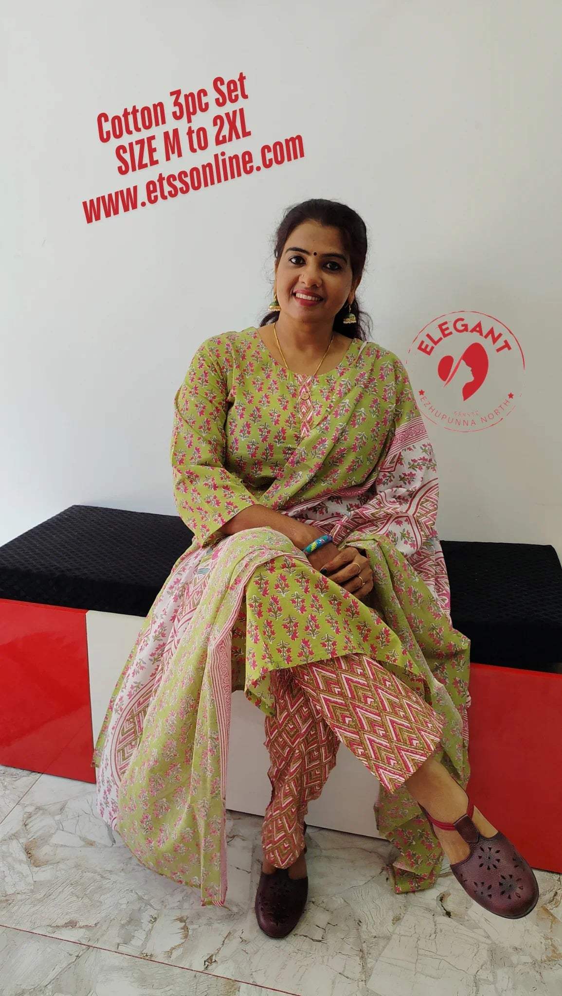Women wearing green and pink cotton churidar set with printed kurta and patterned dupatta, seated on black and red bench.