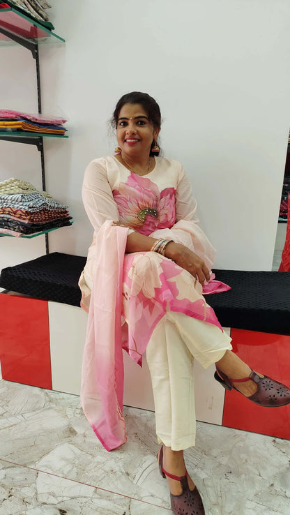 Woman wearing pink and cream churidar set with floral design sitting indoors