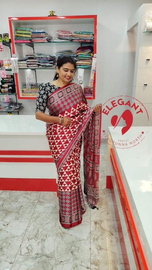 Woman wearing a red and white semi modal silk saree with geometric patterns in a fabric store showcasing Semi Modal Silk Sarees.
