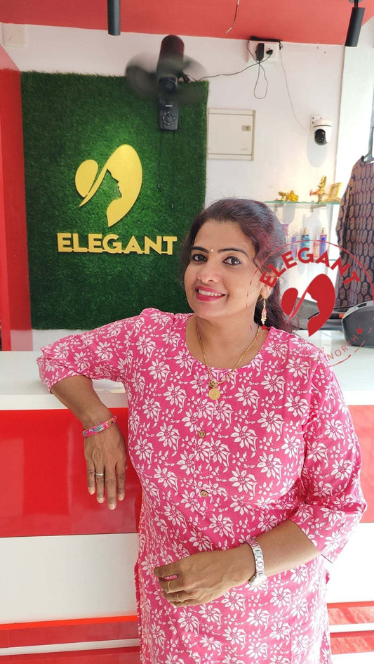 Woman wearing pink floral Kurthi Set standing indoors with Elegant logo in background