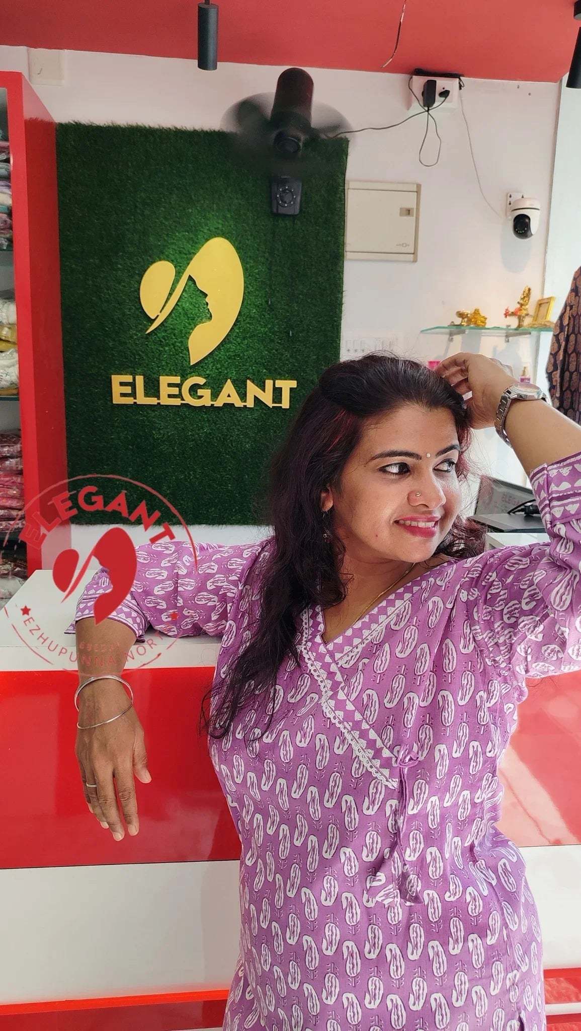 Woman wearing a purple cotton Kurthi Set with white patterns, posing indoors in front of an Elegant store sign