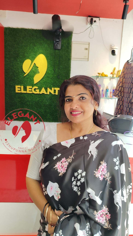 Woman wearing a black satin silk saree with white and pink floral and bird patterns in an Elegant store setting