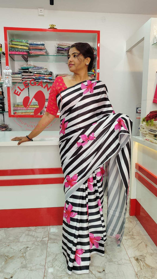 Woman wearing a satin silk saree with black and white stripes and pink floral prints in a boutique setting