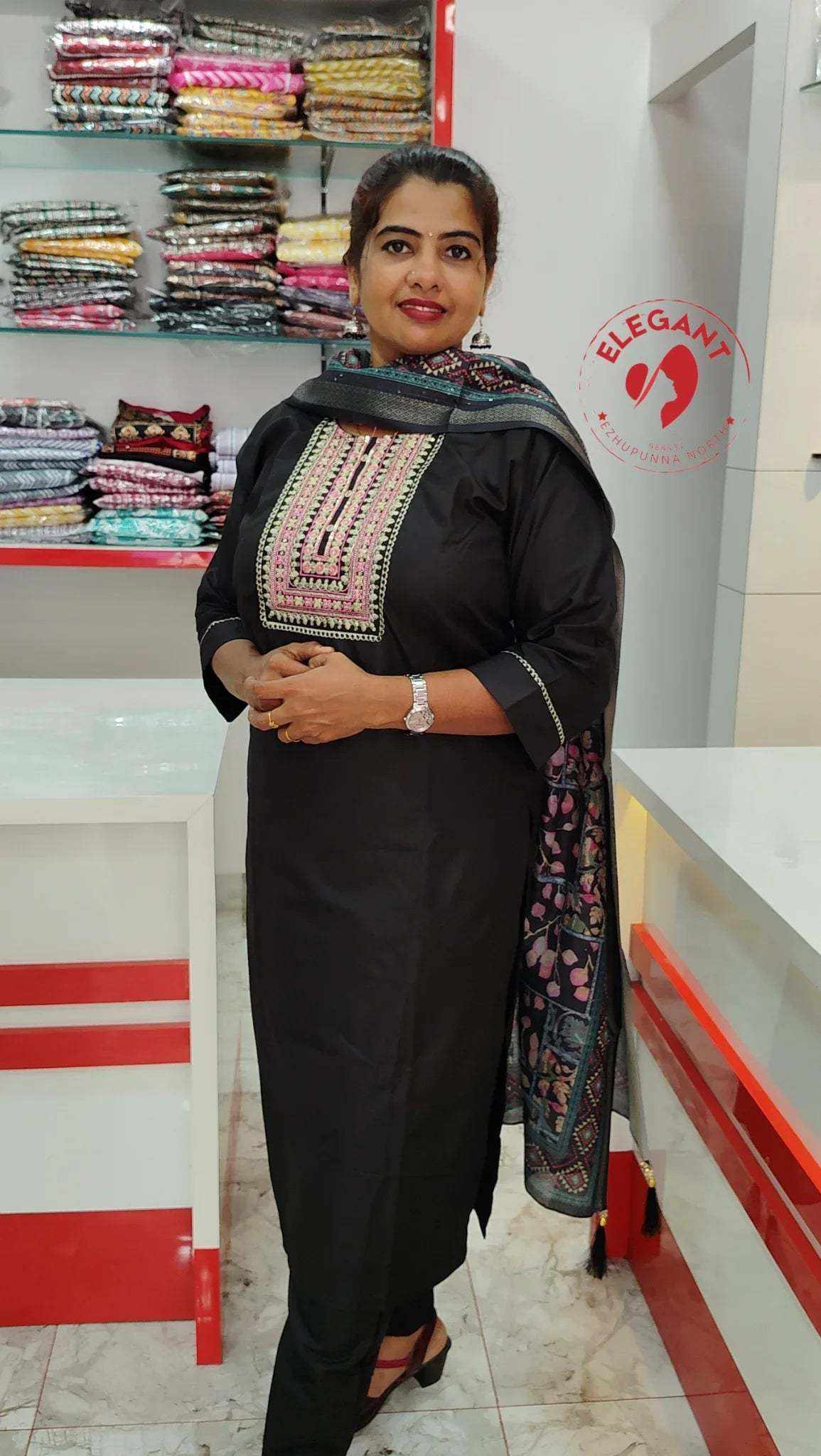 Woman wearing black Roman Silk churidar with embroidered neckline and printed dupatta in a fabric store