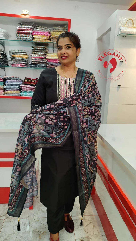 Woman wearing elegant Roman Silk Churidar with intricate floral patterns in a clothing store.
