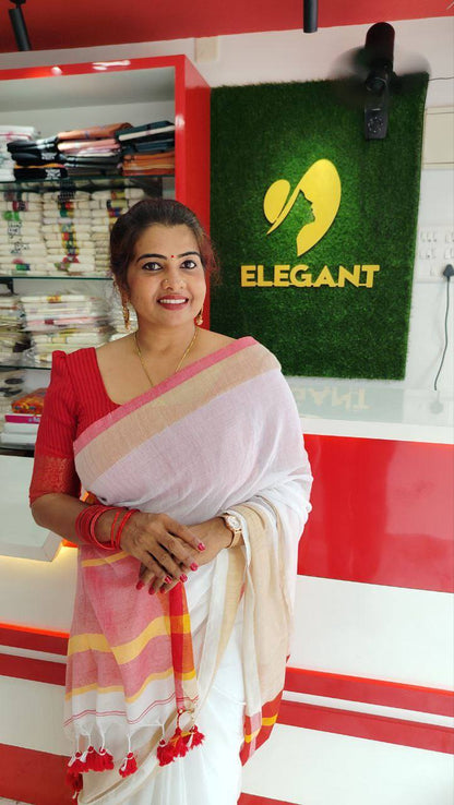 Woman wearing a traditional Mul Cotton Set Saree with kasavu border and rich red pallu with tassels standing in a clothing store.