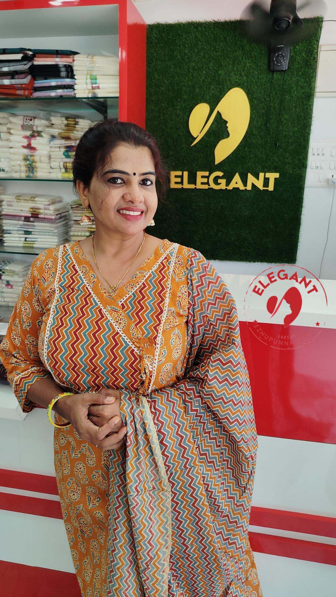 Woman wearing a cotton churidar set in orange with multicolor zigzag patterned dupatta at Elegant store background