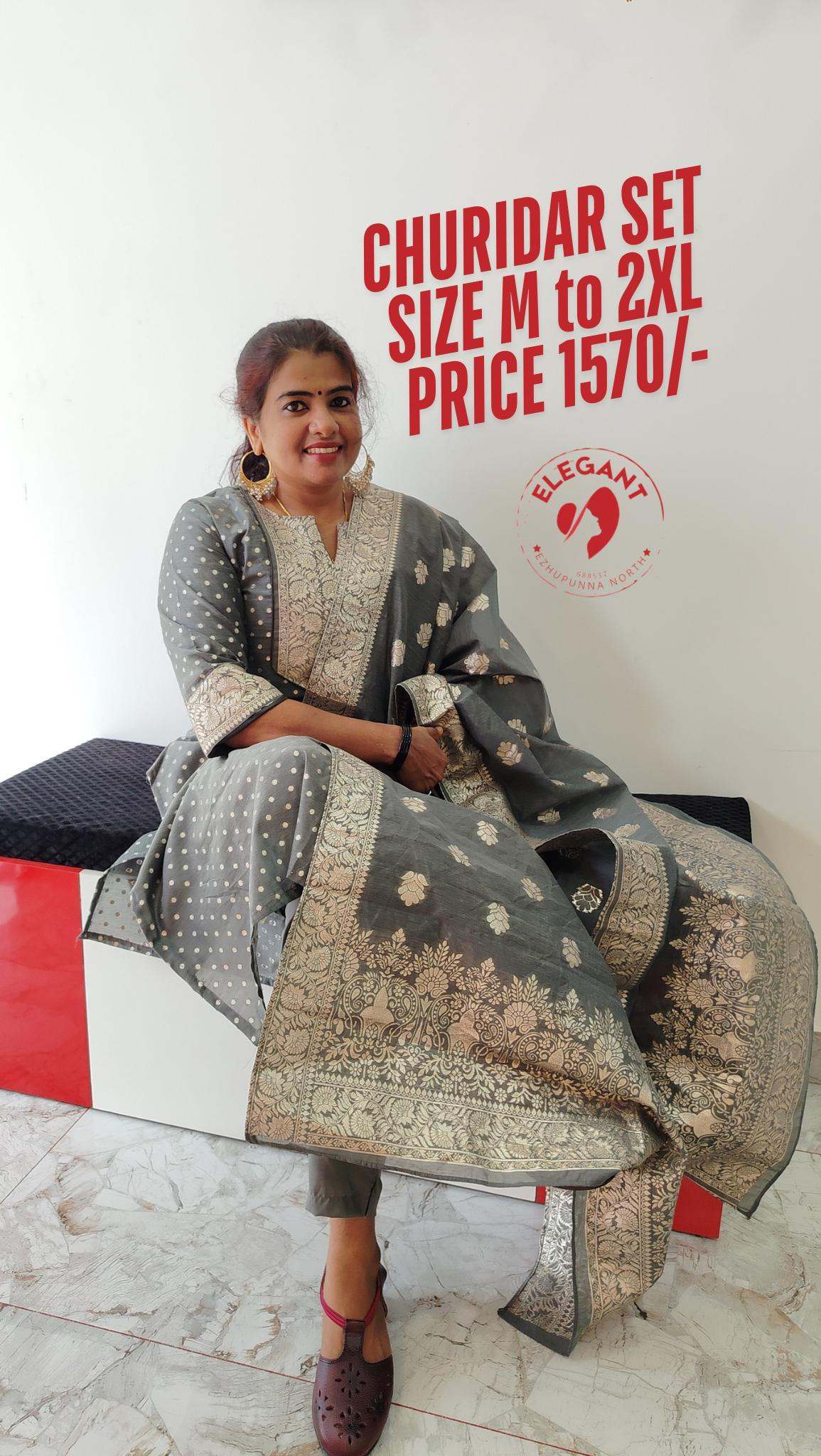 Woman wearing elegant grey silk party wear churidar with gold embroidery sitting on a bench