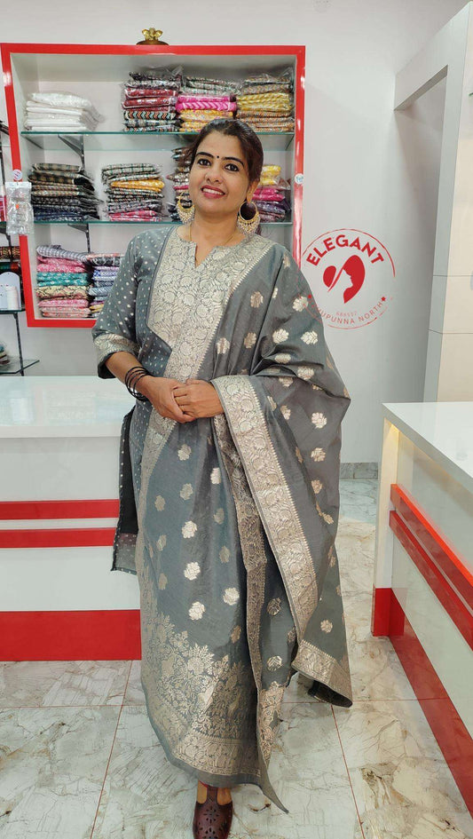 Woman wearing elegant grey silk party wear churidar with silver embroidery in a boutique setting