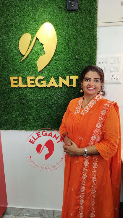 Woman wearing orange churidar set standing by Elegant store sign