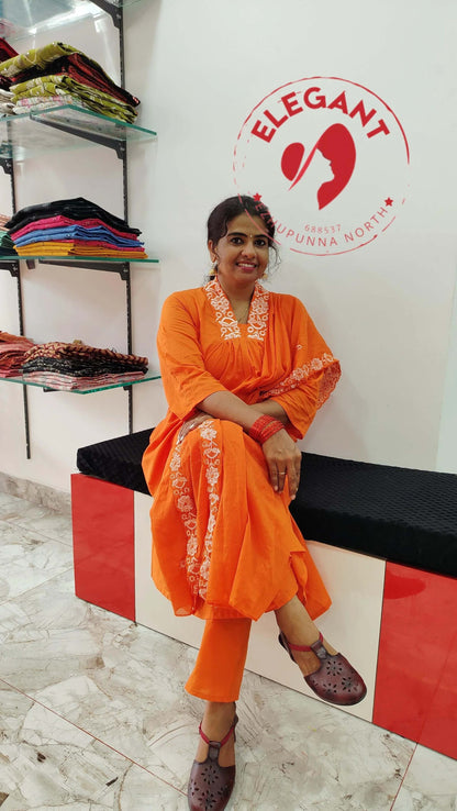Woman wearing orange cotton churidar set with white embroidery sitting in boutique showroom