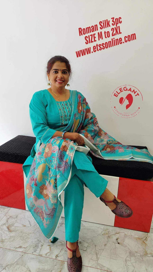 Woman wearing turquoise Roman Silk Churidar with floral patterned dupatta, sitting and smiling indoors