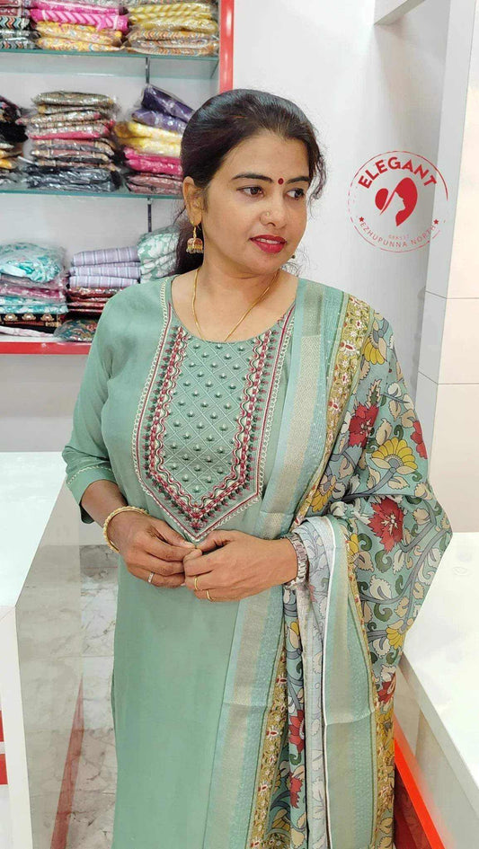 Woman wearing elegant Roman silk churidar with intricate embroidery and floral patterned dupatta in a fabric store interior