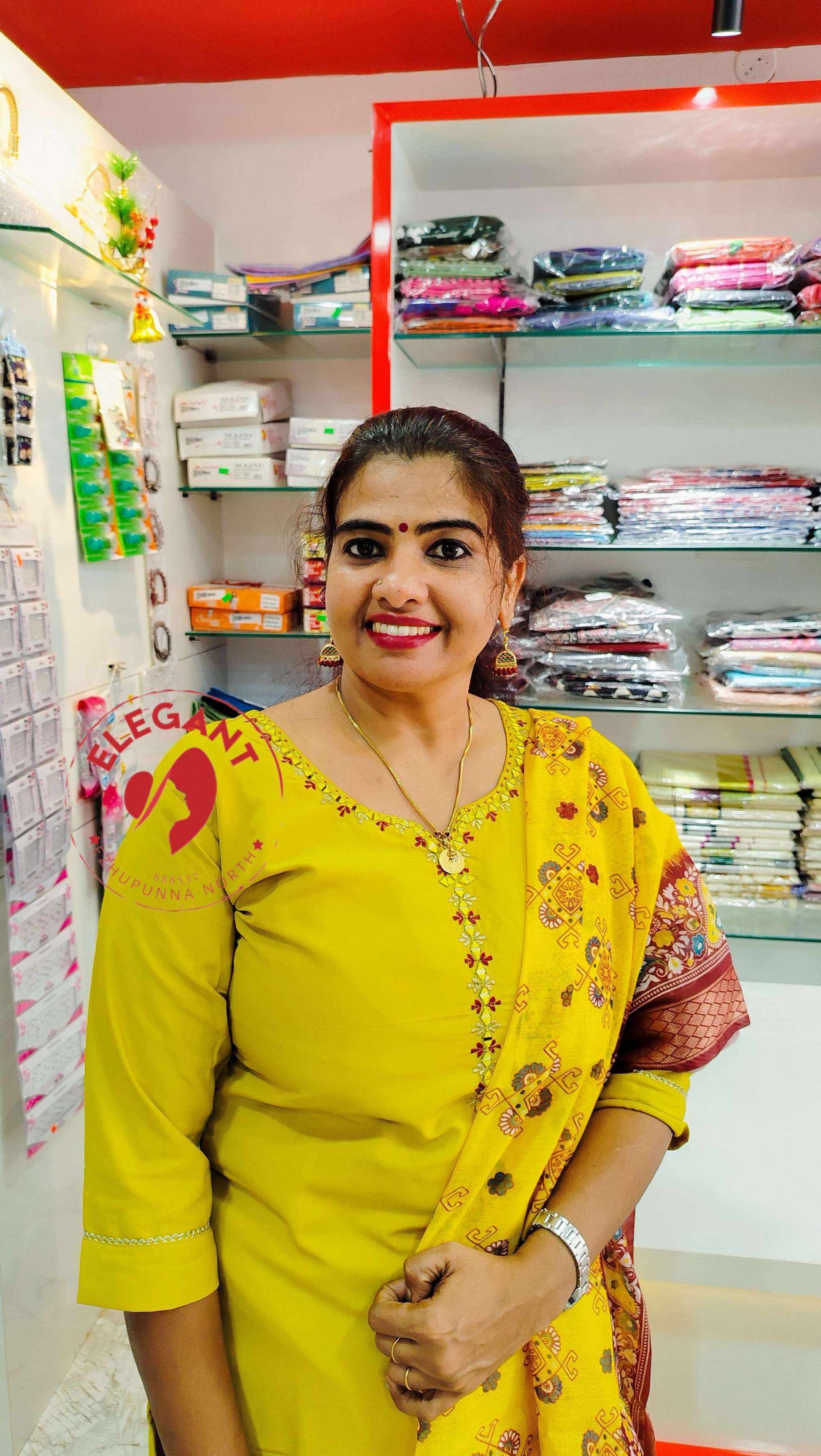 Woman in yellow Roman silk churidar standing in fabric store with shelves of folded textiles