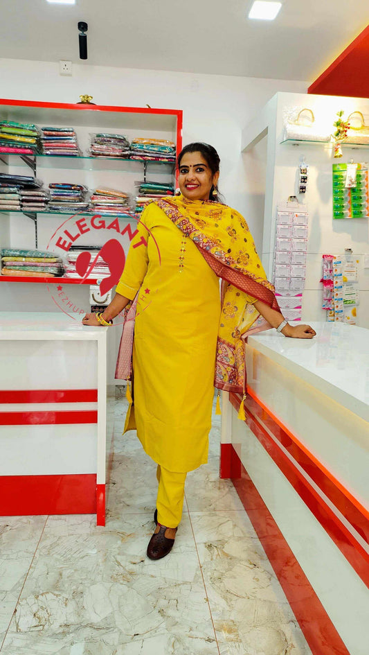 Woman wearing yellow Roman silk churidar standing in a fabric store with colorful folded fabrics in the background