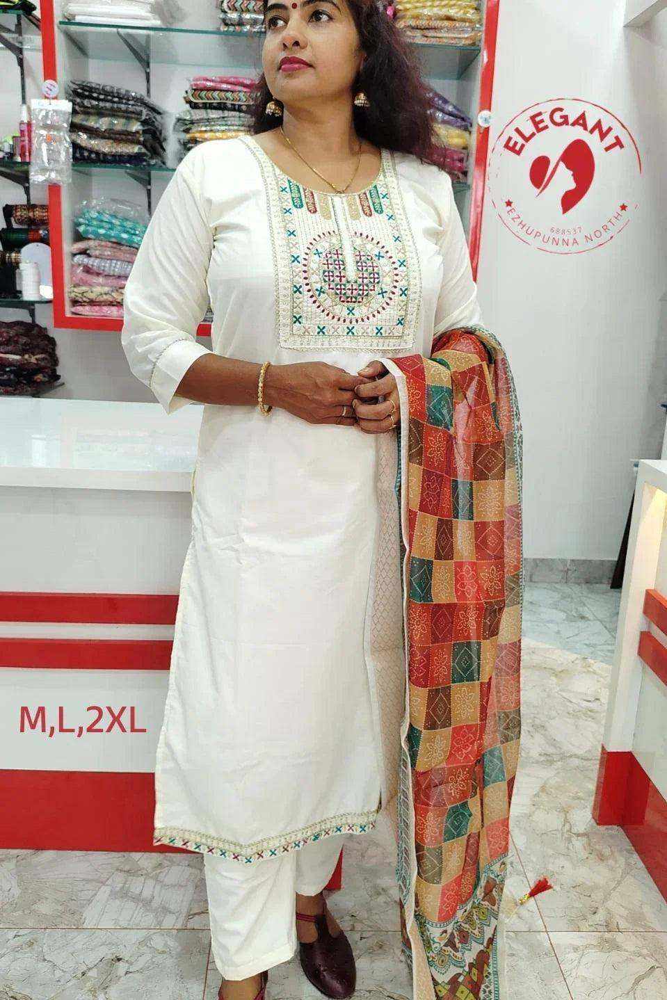 Woman wearing a white Roman Silk churidar with embroidered neckline and multicolor patterned dupatta in a clothing store.