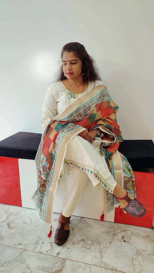 Woman wearing elegant Roman Silk churidar with colorful patterned dupatta sitting indoors